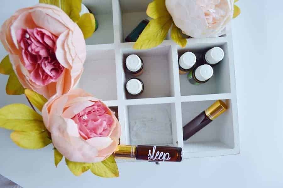 Image of a white box with essential oils and peonies in it. 