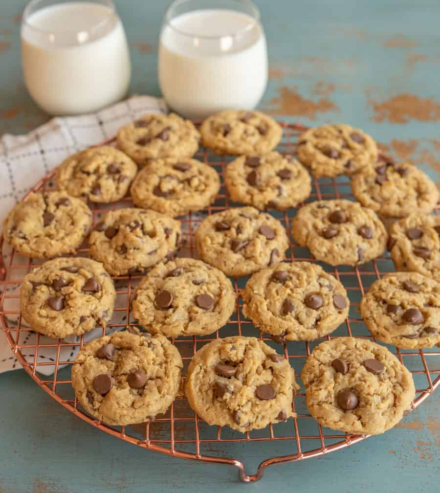 AN angled photo of peanut butter chocolate chip oatmeal cookies on a cooling rack in front of a glass of milk.