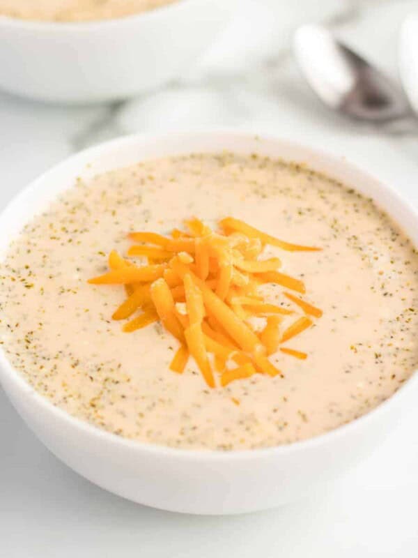 a bowl of cheesy broccoli soup topped with a little bit of grated cheddar cheese.