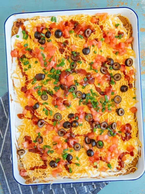 Bring the fiesta to your taste buds with this classic rendition of everyone's favorite Bean Dip. Refried beans, sour cream, cheese, tomatoes, black olives, and green onion meld with taco seasoning and salsa for a festive kick that's sure to impress.