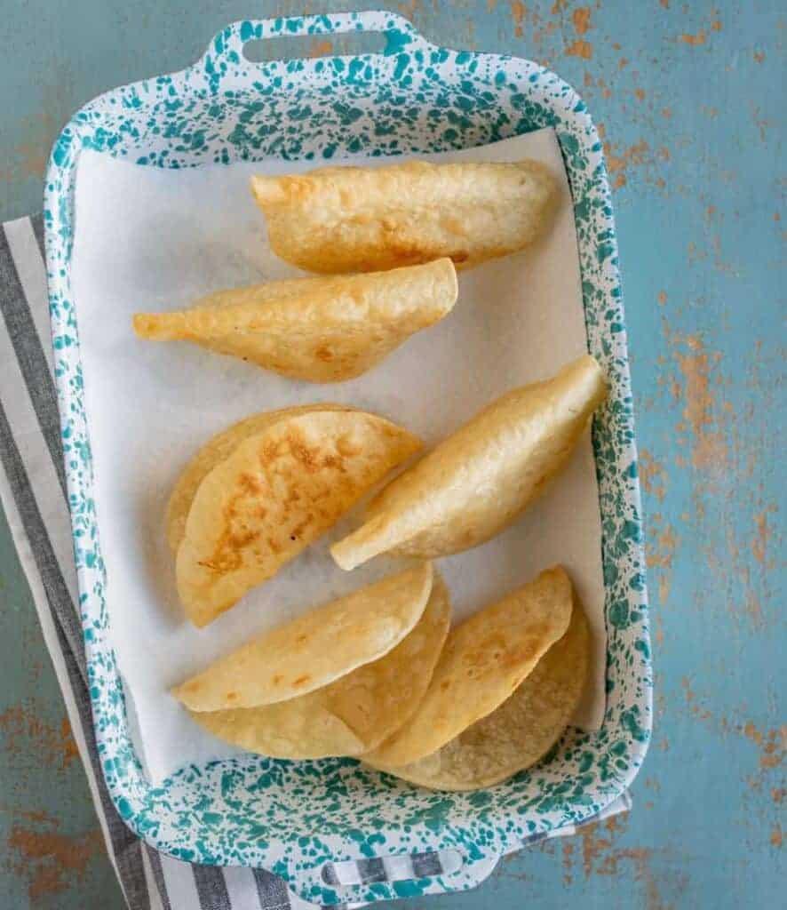an overhead shot of corn tortilla taco shells in a pan.