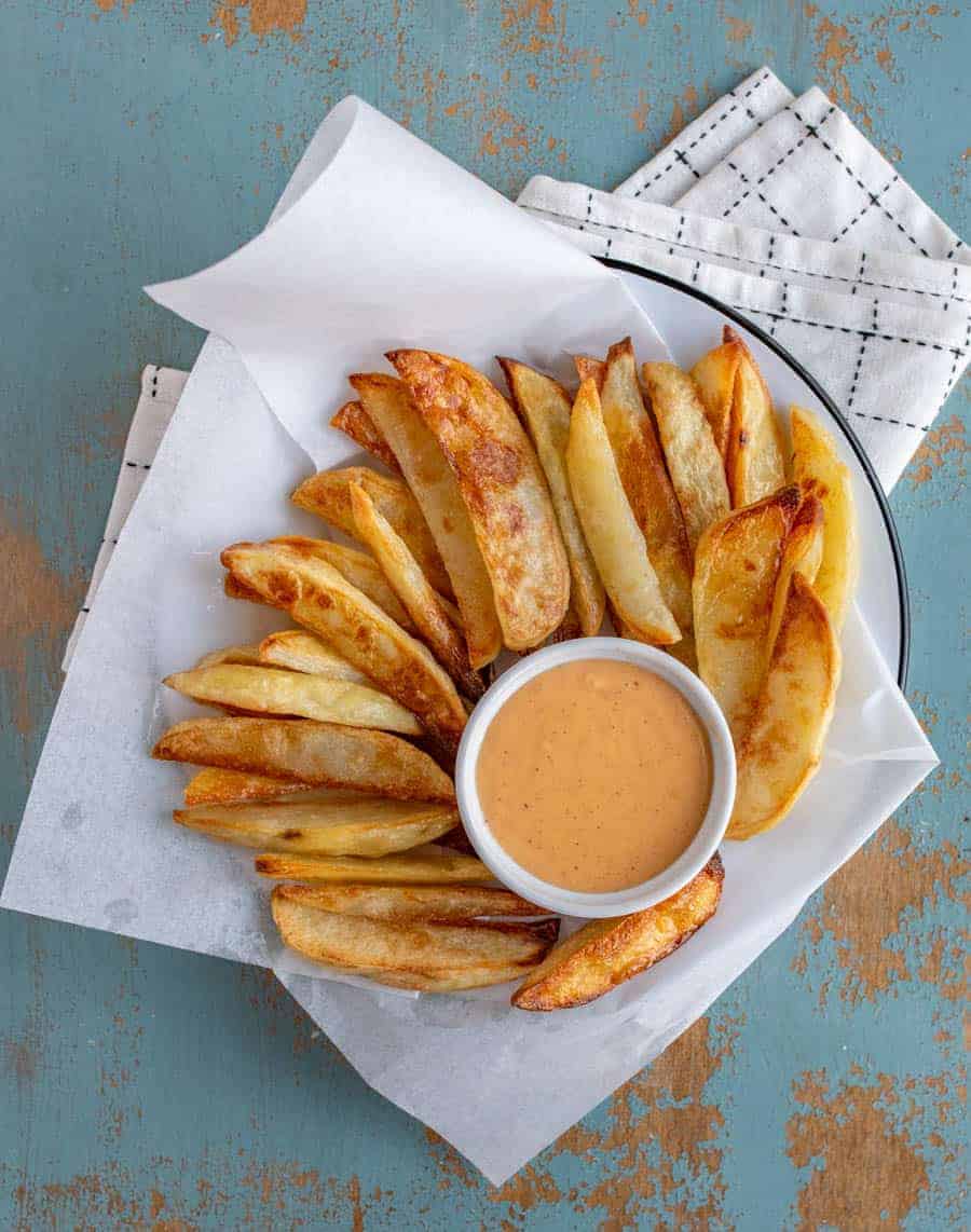 an overhead shot of oven baked French fries on a plate along with a small bowl of fry sauce.