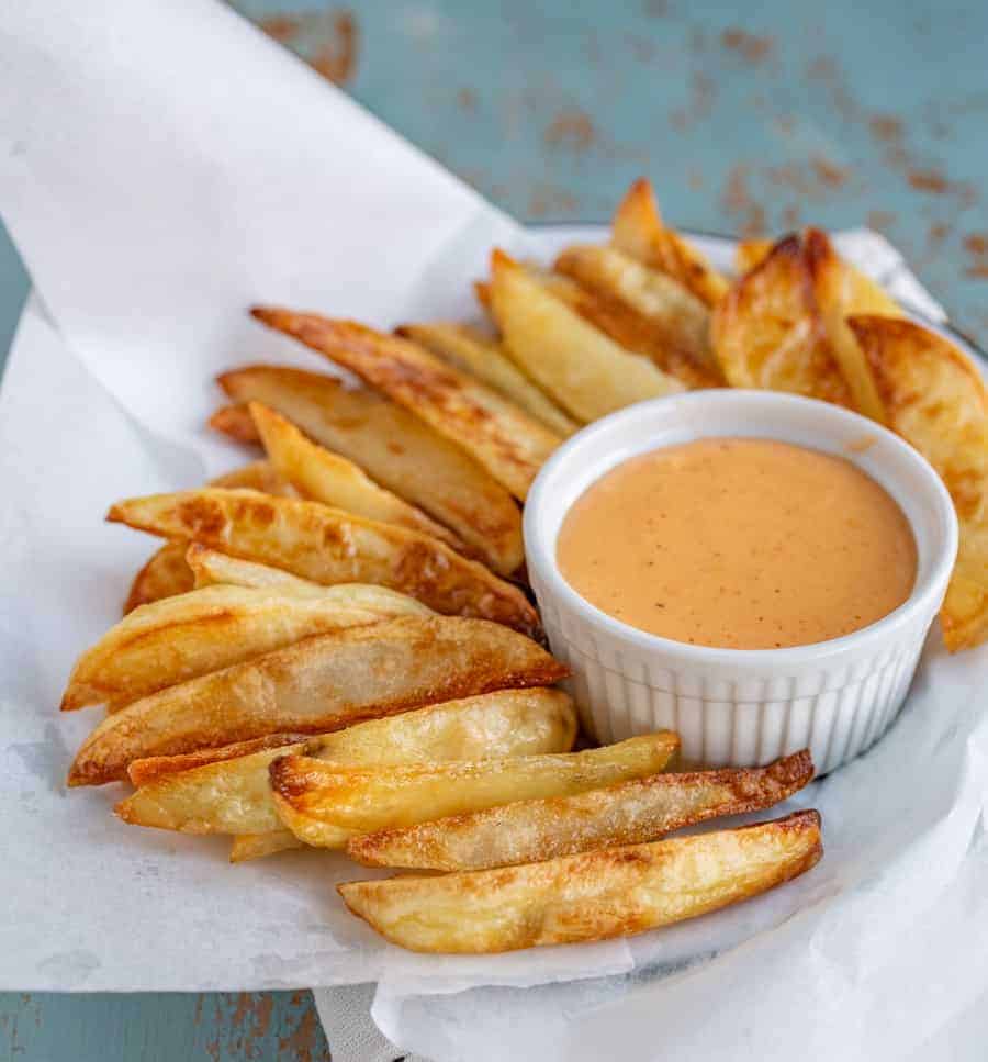 a plate of crispy oven French fries served with a small bowl of fry sauce.