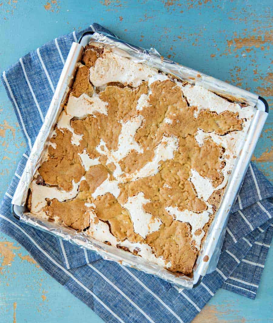 tan and white cookie bars in a pan on top of a blue towel.