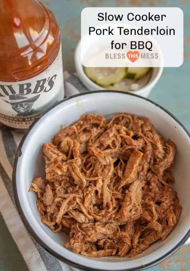 Title Image for Slow Cooker Pork Tenderloin for BBQ with a bottle of BBQ sauce and a white bowl filled with shredded BBQ pork
