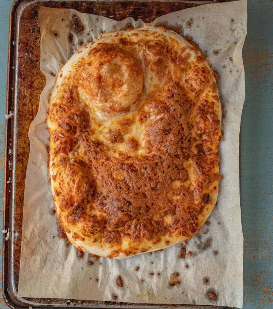 A whole no-knead pizza that has been topped with cheese and baked until golden brown.