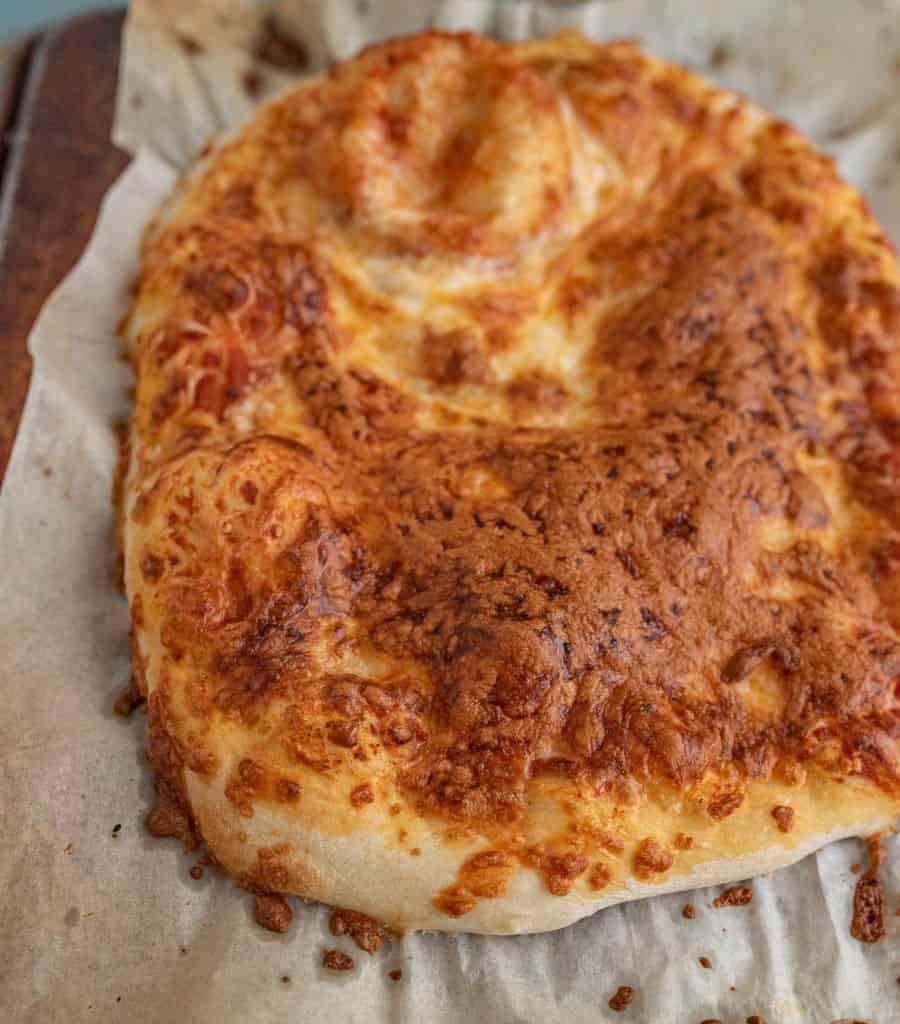 close-up shot of no knead pizza dough baked and topped with cheese.