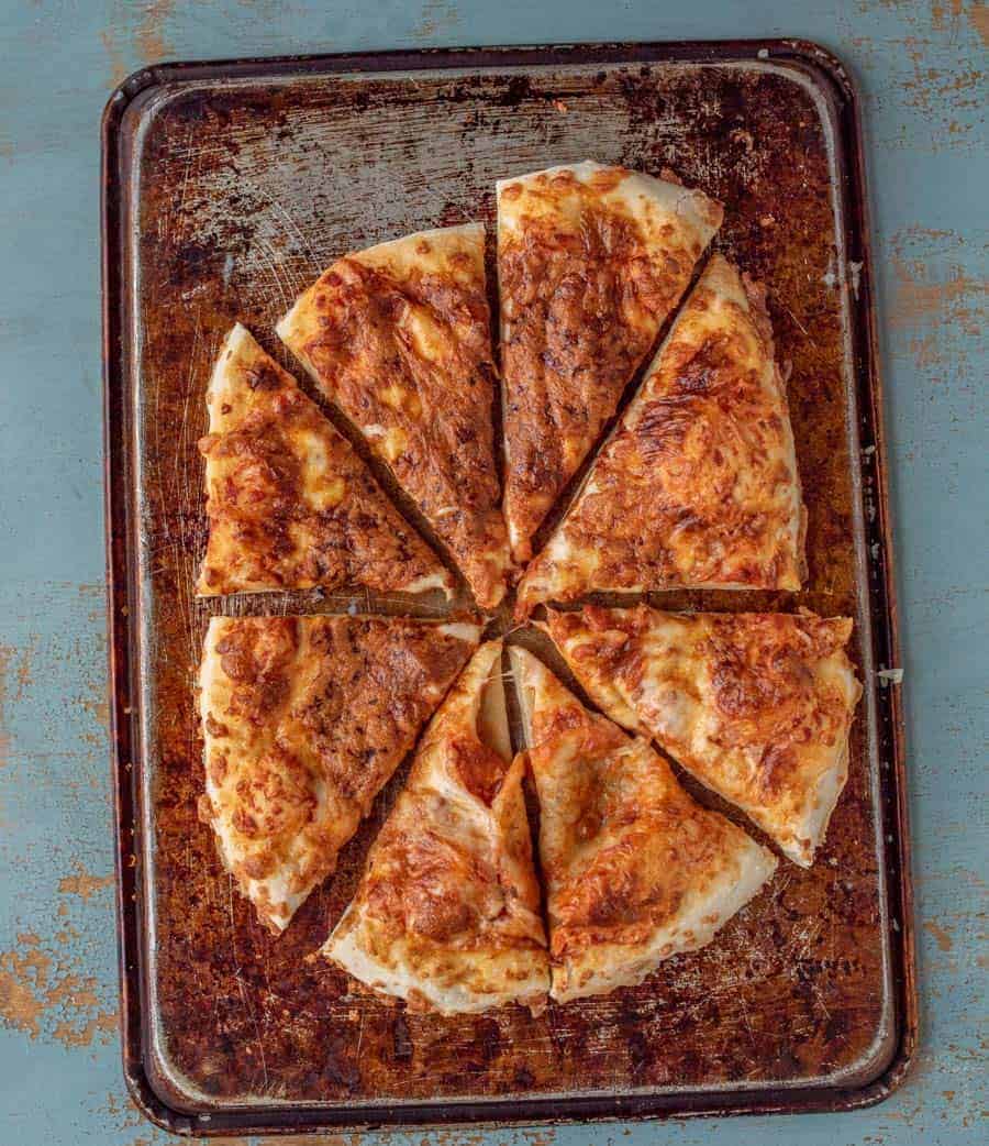 An overhead shot of this no-knead pizza dough topped with cheese and baked until golden brown. Sliced.