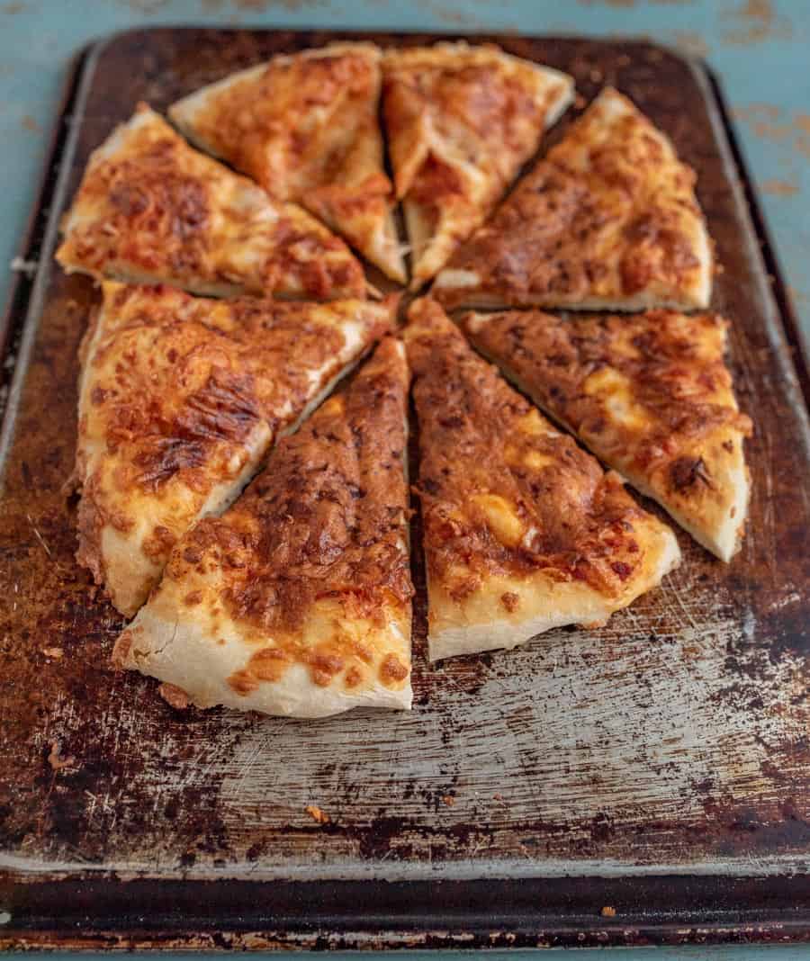 close-up of sliced no knead pizza that has been topped with cheese and baked until golden brown.