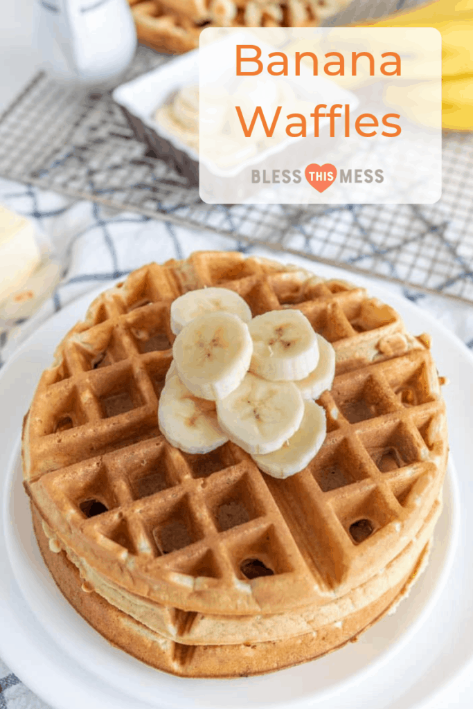 A stack of banana waffles topped with fresh slices sits enticingly on a white plate. The text overlay reads Banana Waffles with Bless This Mess beneath it, capturing the delightful chaos. In the background, a waffle iron and ripe bananas complete this delicious scene.