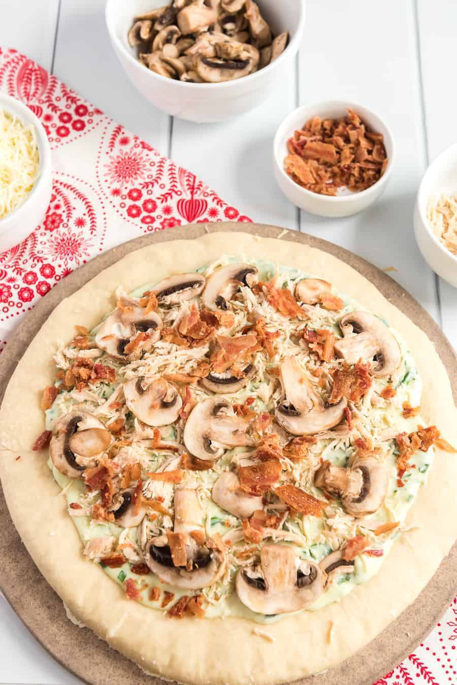 Take your homemade pizza to new heights with this recipe featuring chicken, bacon, and mushrooms slathered in melted cheese and creamy sauce.