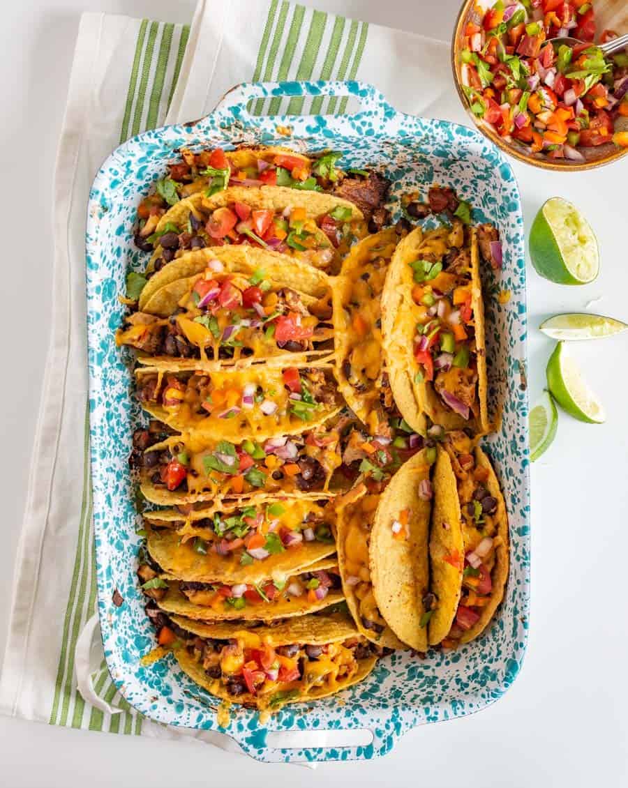 Crispy and Crunchy Baked Chicken Tacos are a quickly thrown-together and satisfying meal, complete with baked chicken, taco seasoning, black beans, hard taco shells, and plenty of shredded cheddar cheese.