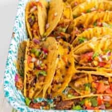 Crispy and Crunchy Baked Chicken Tacos are a quickly thrown-together and satisfying meal, complete with baked chicken, taco seasoning, black beans, hard taco shells, and plenty of shredded cheddar cheese.