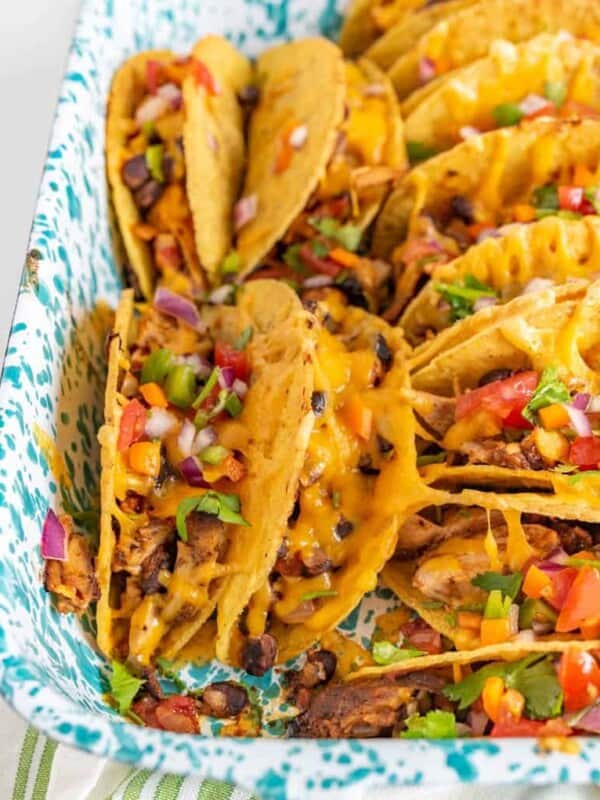 Crispy and Crunchy Baked Chicken Tacos are a quickly thrown-together and satisfying meal, complete with baked chicken, taco seasoning, black beans, hard taco shells, and plenty of shredded cheddar cheese.