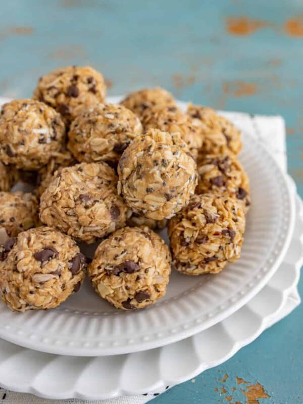 balls of oats, peanut butter, chocolate chips, and other ingredients on a white plate set on a white and white towel.