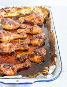 chicken legs on a sheet pan with sauce.