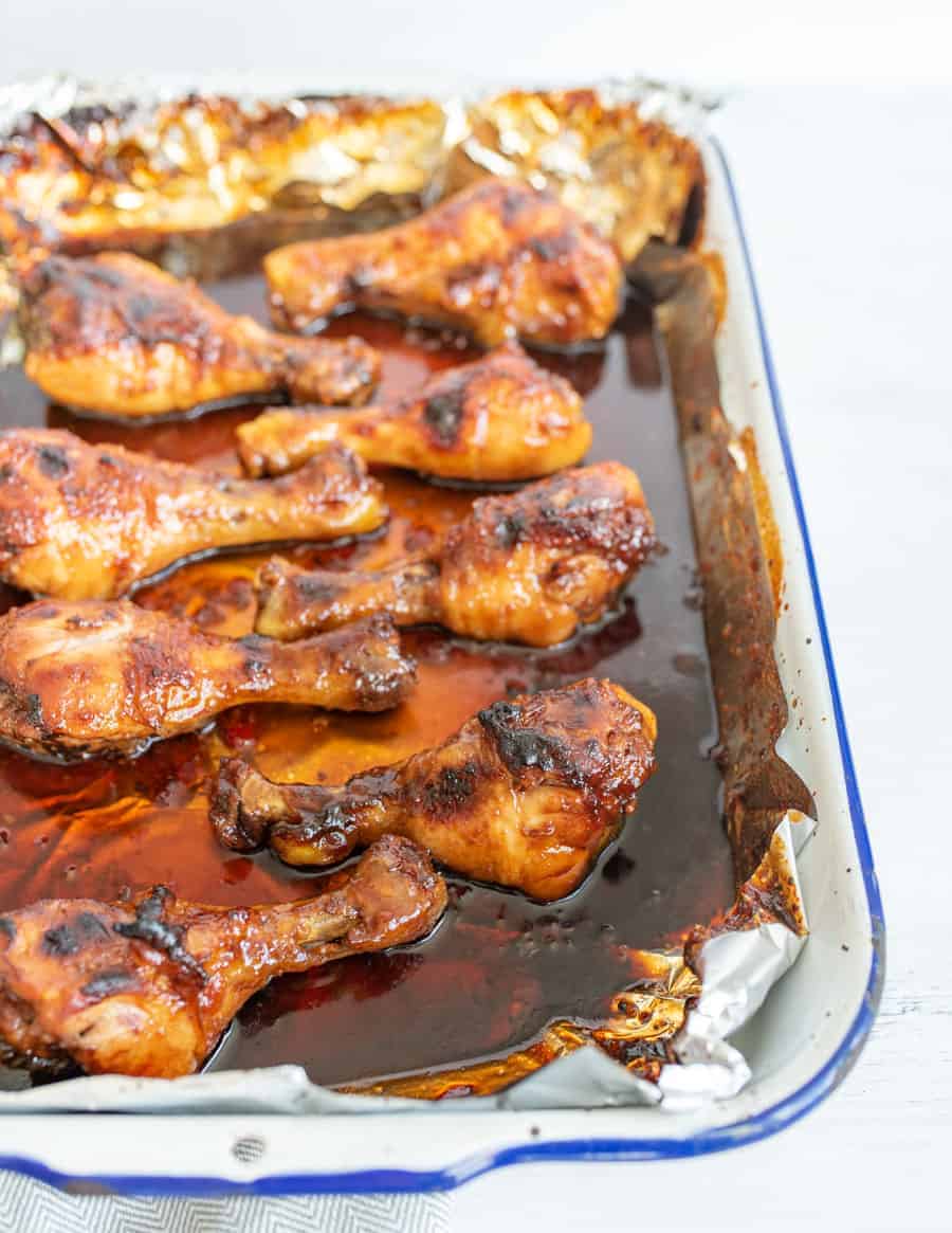 side view of multiple chicken drumsticks in the pan they cooked in