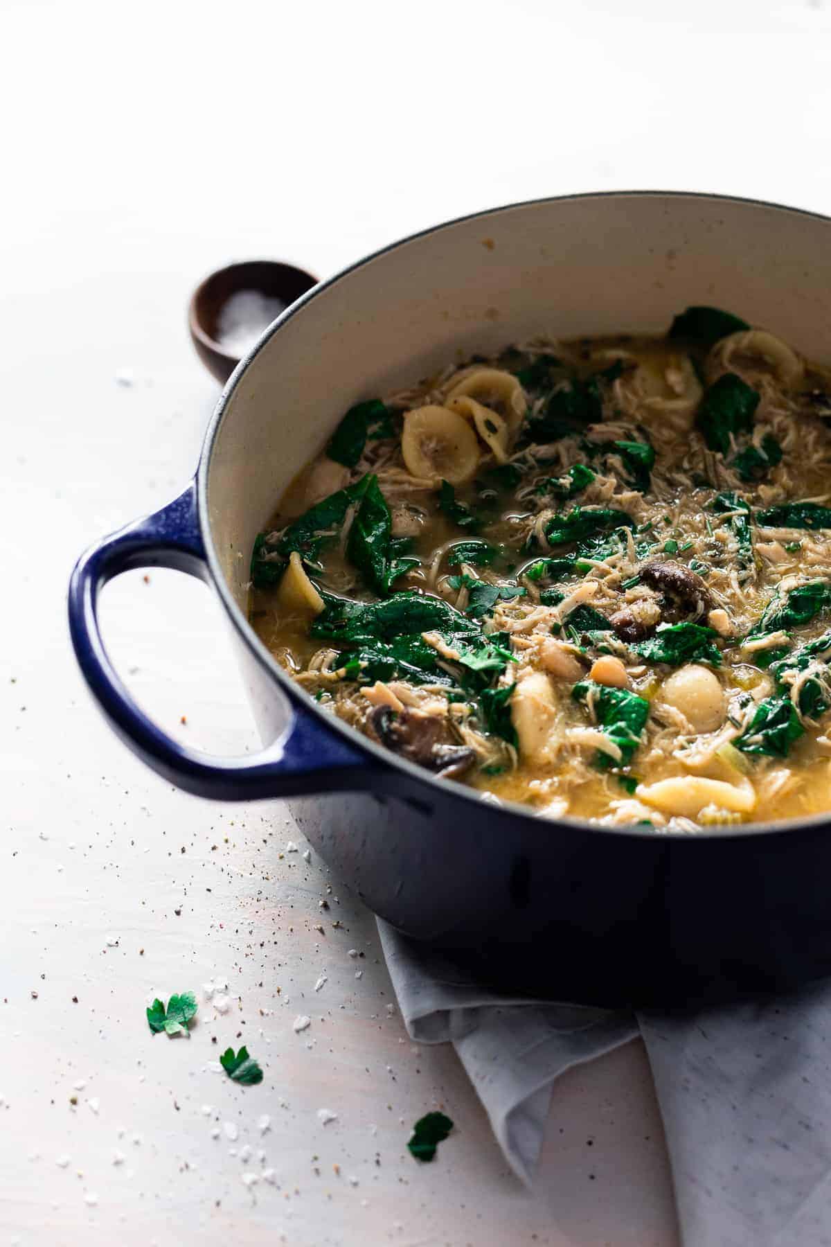 soup with pasta, mushrooms herbs and chicken in a blue Dutch oven.