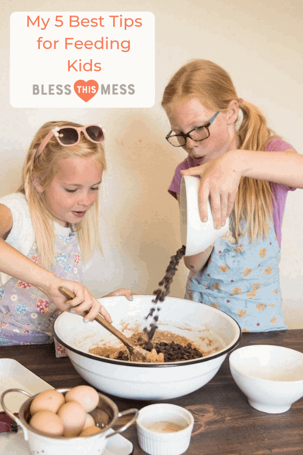 two young girls mixing and pouring chocolate chips into batter