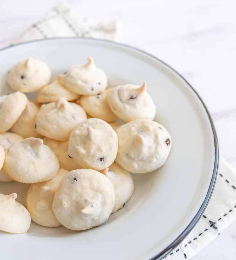 white and chocolate drop meringue cookies in a white bowl.