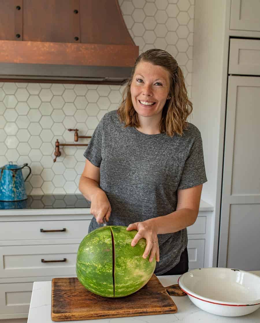 melisa in her kitchen cutting a watermelon in half