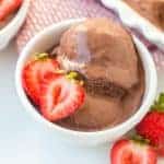 dark chocolate ice cream with halved strawberries in a small white dish