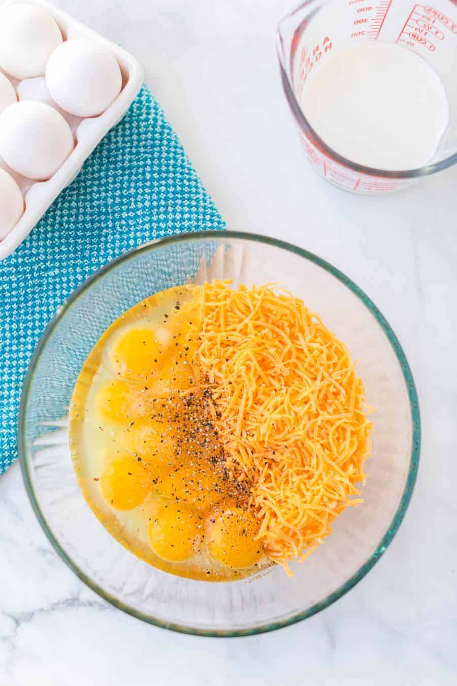 eggs and cheese as the start of quiche mix in a clear glass bowl