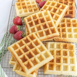 buttermilk waffles on a plate with syrup and strawberries.