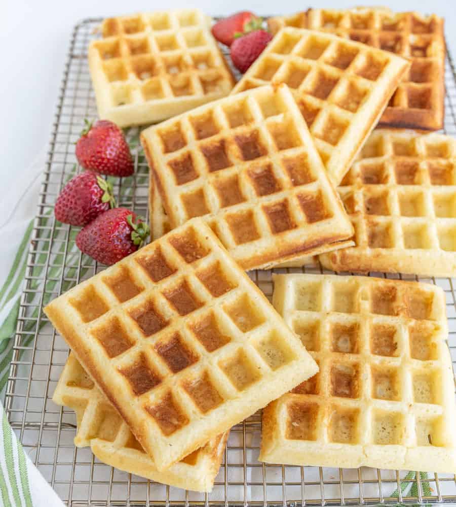 buttermilk waffles on a plate with syrup and strawberries.