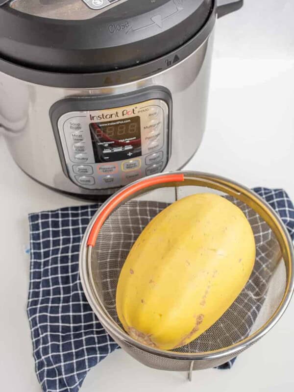 whole spaghetti squash in a strainer near the instant pot