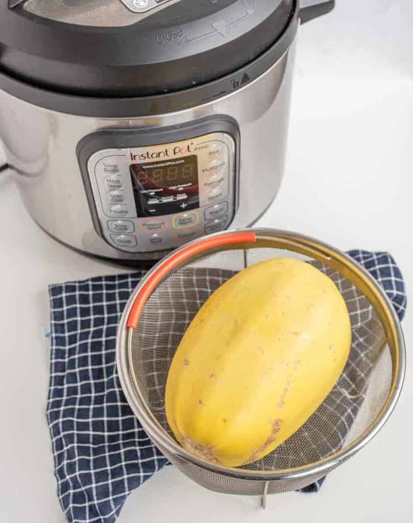 whole spaghetti squash in a strainer near the instant pot