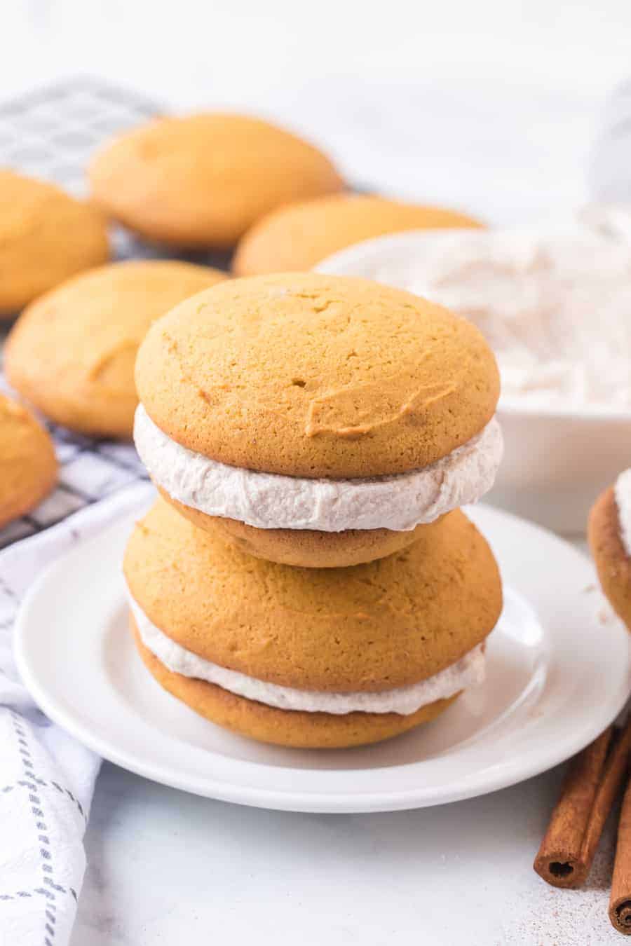 Brace yourselves for bites of heaven -- these pumpkin whoopie pies with whipped cinnamon filling are the perfectly sweet and soft, cream-filled cookie sandwiches you need this fall... and probably year-round, too. #whoopiepie #whoopiepierecipe #pumpkinwhoopiepie #pumpkin #pumkpindessert #pumpkinrecipe