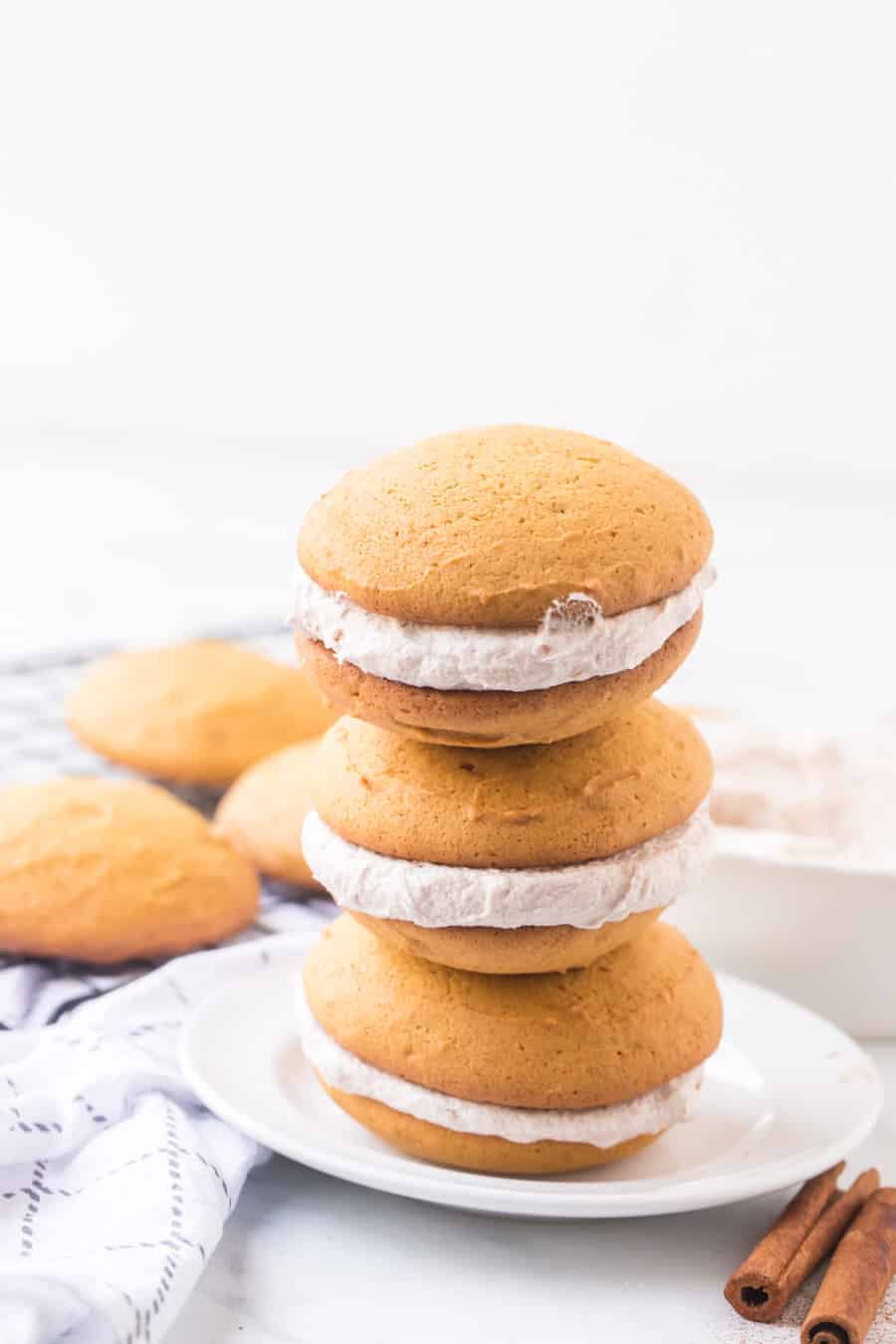 Brace yourselves for bites of heaven -- these pumpkin whoopie pies with whipped cinnamon filling are the perfectly sweet and soft, cream-filled cookie sandwiches you need this fall... and probably year-round, too. #whoopiepie #whoopiepierecipe #pumpkinwhoopiepie #pumpkin #pumkpindessert #pumpkinrecipe