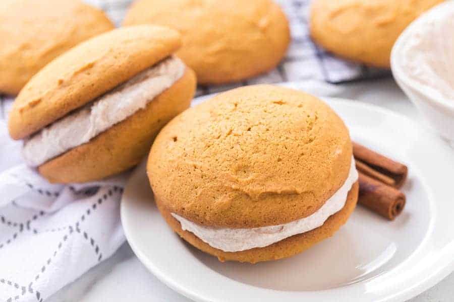 Brace yourselves for bites of heaven -- these pumpkin whoopie pies with whipped cinnamon filling are the perfectly sweet and soft, cream-filled cookie sandwiches you need this fall... and probably year-round, too. #whoopiepie #whoopiepierecipe #pumpkinwhoopiepie #pumpkin #pumkpindessert #pumpkinrecipe