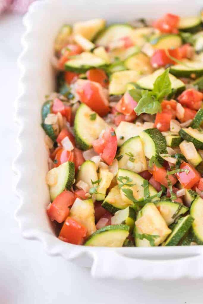 zucchini and tomato in a baking pan for a side dish with zucchini recipe.