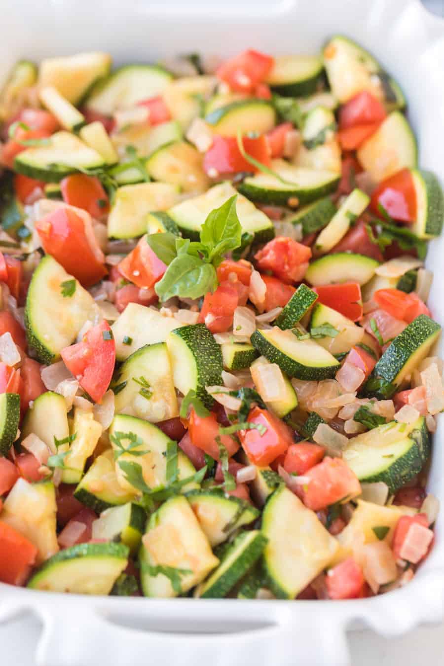 This zucchini side dish is full of onion, tomato, herbs, and of course zucchini to make a bright and fresh side that tastes out-of-this-world delicious! #zucchini #zucchiniside #easyzucchinirecipe #zucchinimedley