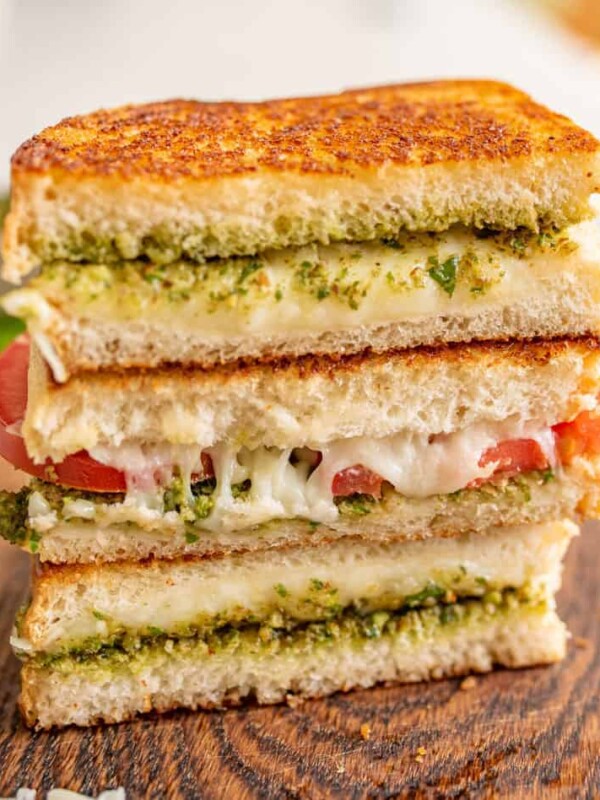 pesto grilled cheese and tomato sandwiches sliced revealing the melty inside