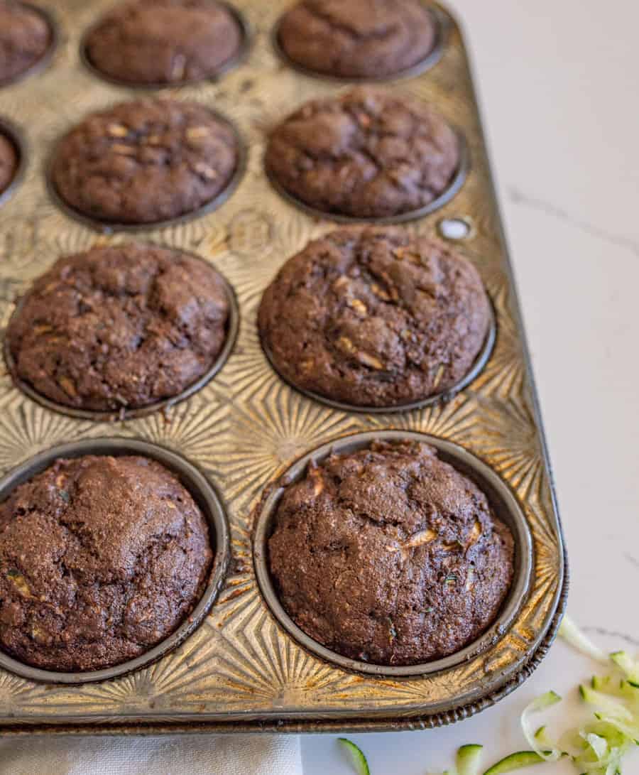 Healthy chocolate zucchini muffins are so yummy and make for a perfect snack or lunchtime dessert, made with whole wheat flour, maple syrup, applesauce, grated zucchini, and mini chocolate chips! #chocolatemuffins #zucchinimuffins #muffins #healthymuffins #muffinrecipe #chocolatezucchinimuffins