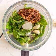 overhead view of basil, seasonings, garlic, and walnuts in a food processor