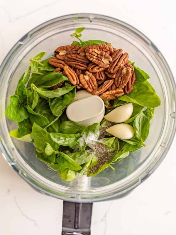 overhead view of basil, seasonings, garlic, and walnuts in a food processor