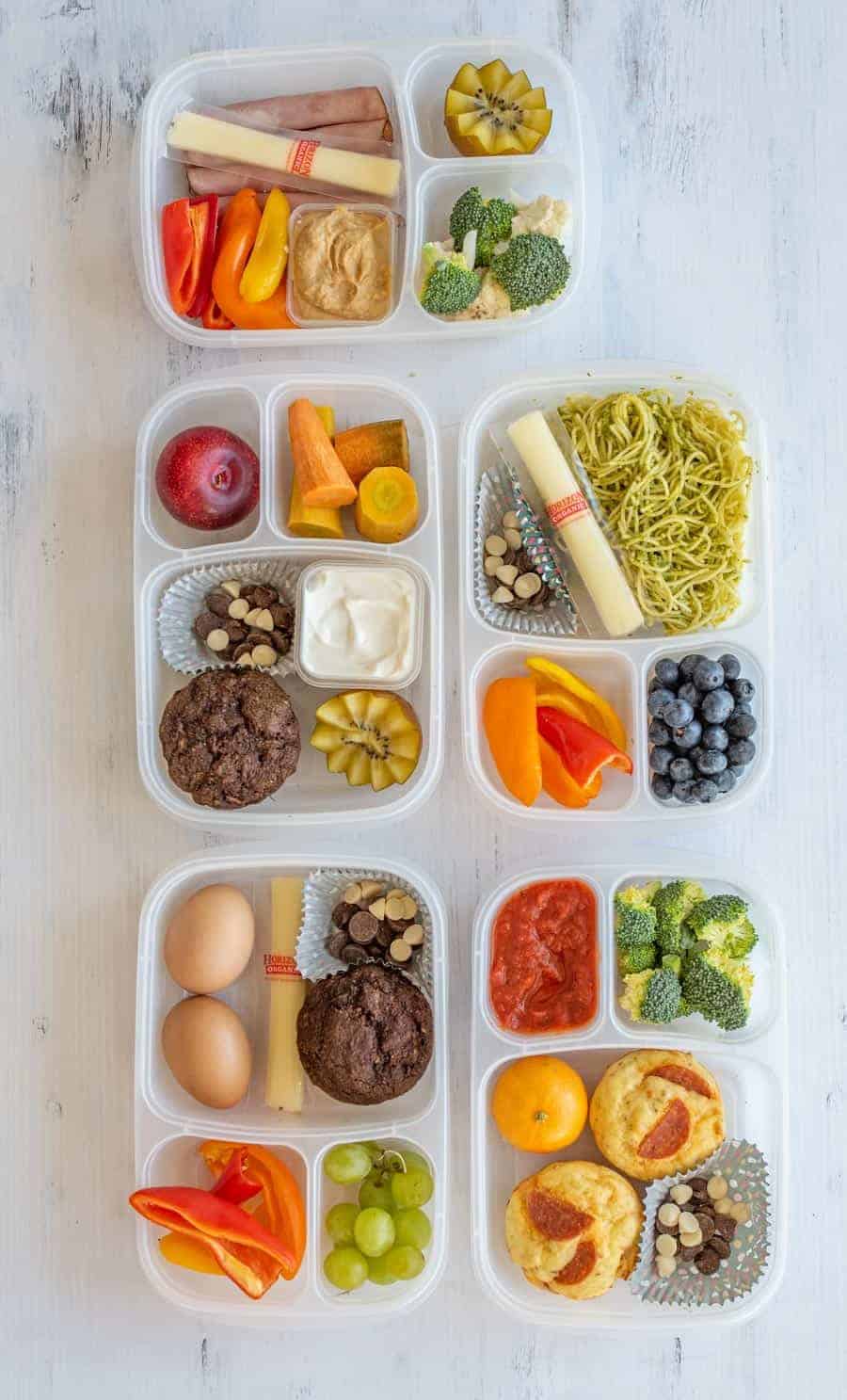 lunch box containers filled with assorted fruits, vegetables, nuts, cheese, and chocolate milk.