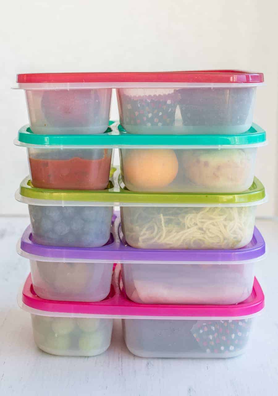 5 plastic compartment containers filled with a variety of foods like fruits and vegetables.