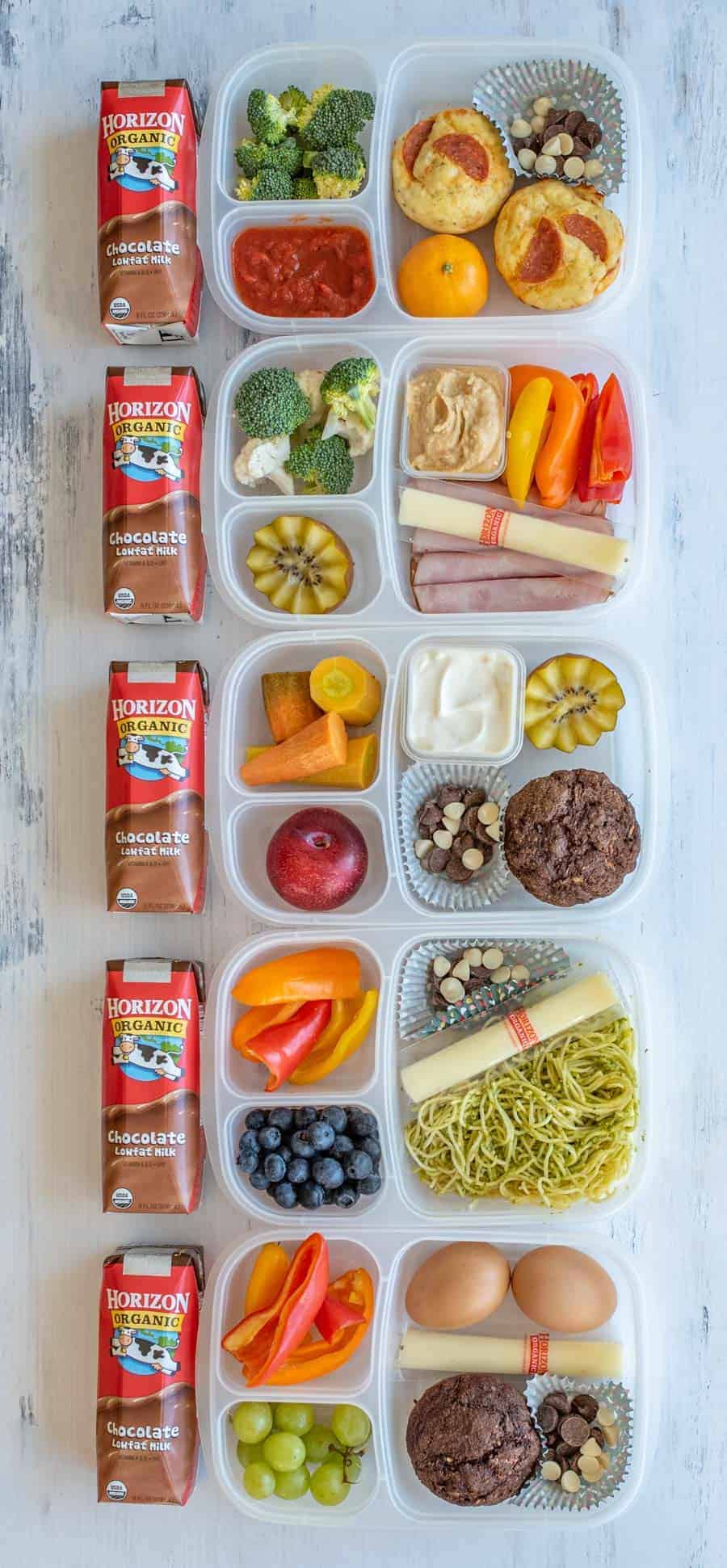 lunch box containers filled with assorted fruits, vegetables, nuts, cheese, and chocolate milk.