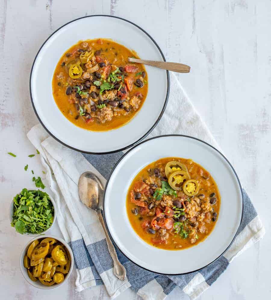 This savory and rich sausage black bean and pumpkin soup is the perfect cool weather dinner that'll fill you up with nourishing ingredients, like black beans, ground sausage, onion, chicken broth, fire-roasted tomatoes, and pumpkin puree. #soup #pumpkinsoup #sausageblackbeansoup #sausageblackbeanpumpkinsoup #fallsouprecipe #chilirecipe #blackbeansoup