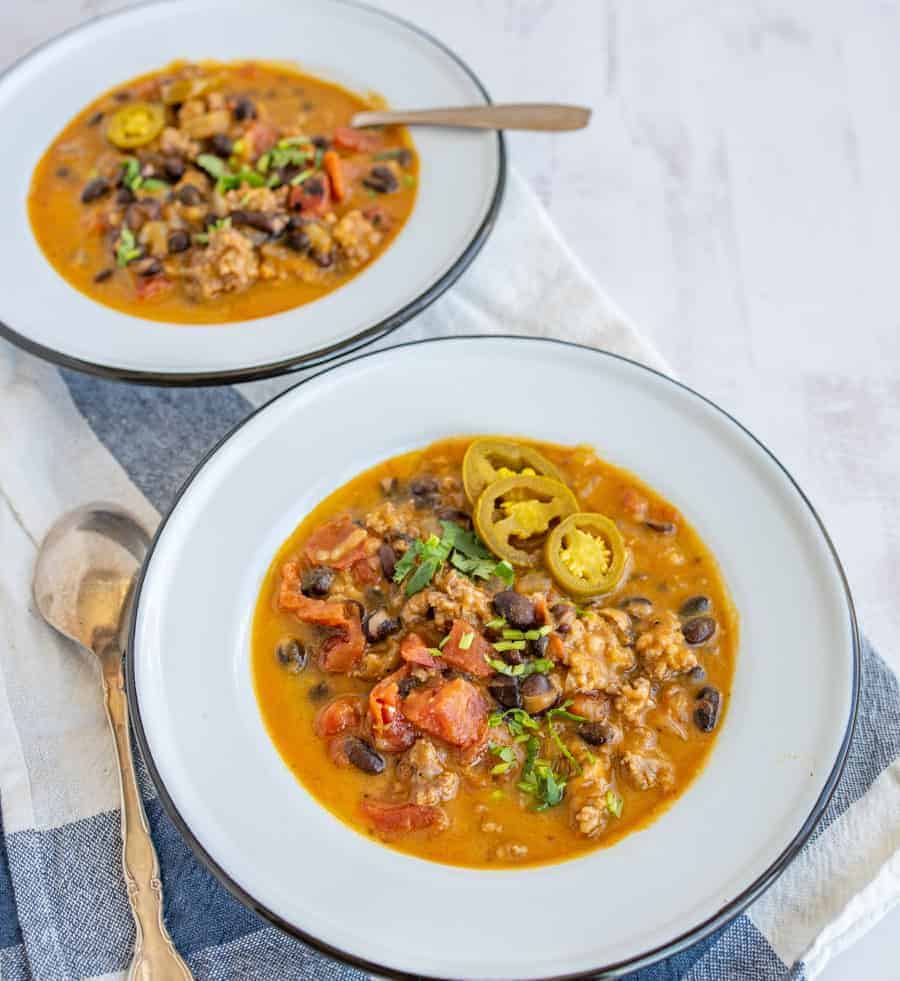 This savory and rich sausage black bean and pumpkin soup is the perfect cool weather dinner that'll fill you up with nourishing ingredients, like black beans, ground sausage, onion, chicken broth, fire-roasted tomatoes, and pumpkin puree. #soup #pumpkinsoup #sausageblackbeansoup #sausageblackbeanpumpkinsoup #fallsouprecipe #chilirecipe #blackbeansoup