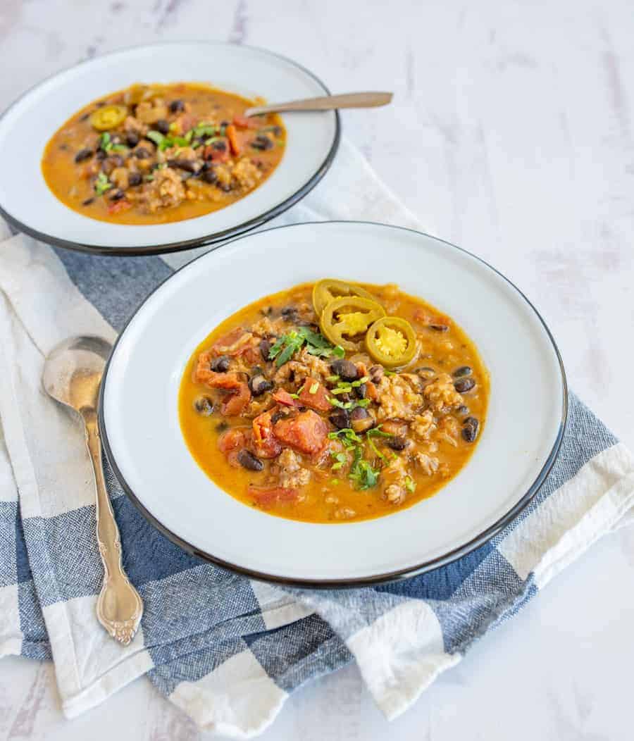 This savory and rich sausage black bean and pumpkin soup is the perfect cool weather dinner that'll fill you up with nourishing ingredients, like black beans, ground sausage, onion, chicken broth, fire-roasted tomatoes, and pumpkin puree. #soup #pumpkinsoup #sausageblackbeansoup #sausageblackbeanpumpkinsoup #fallsouprecipe #chilirecipe #blackbeansoup