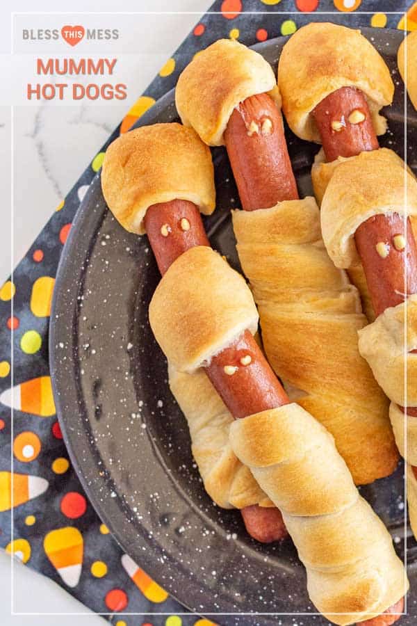 a plate of crescent dough-wrapped hot dogs with mummy faces.