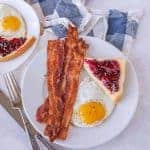 eggs and bacon with a piece of toast with jelly