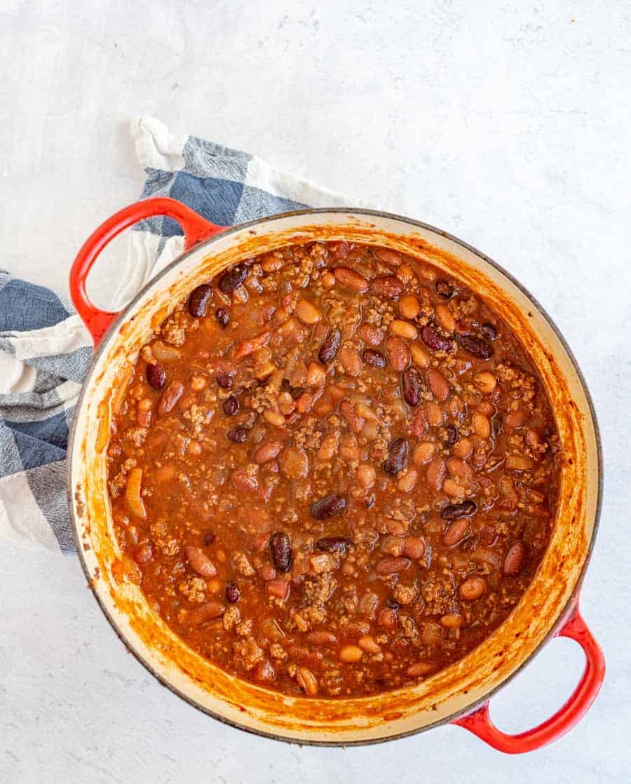 full pot of chili in a large red handled pot