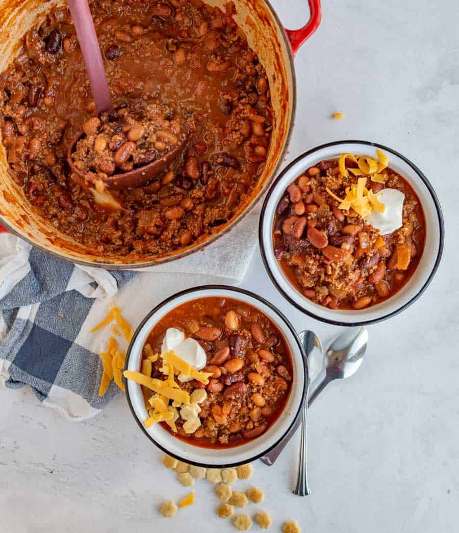 chili in two bowls being served from large dutch oven